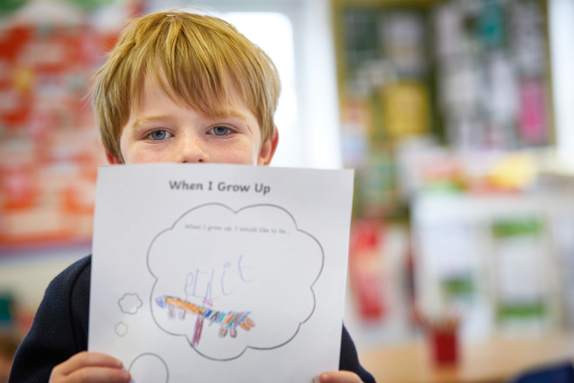 Pupil holding up drawing to illustrate the link to 'Our Community' page
