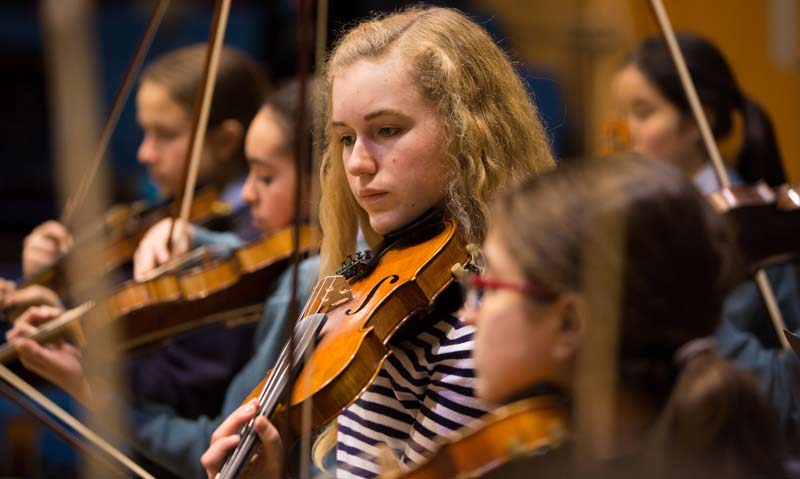 Focus of girl playing a violin in school ochestra 